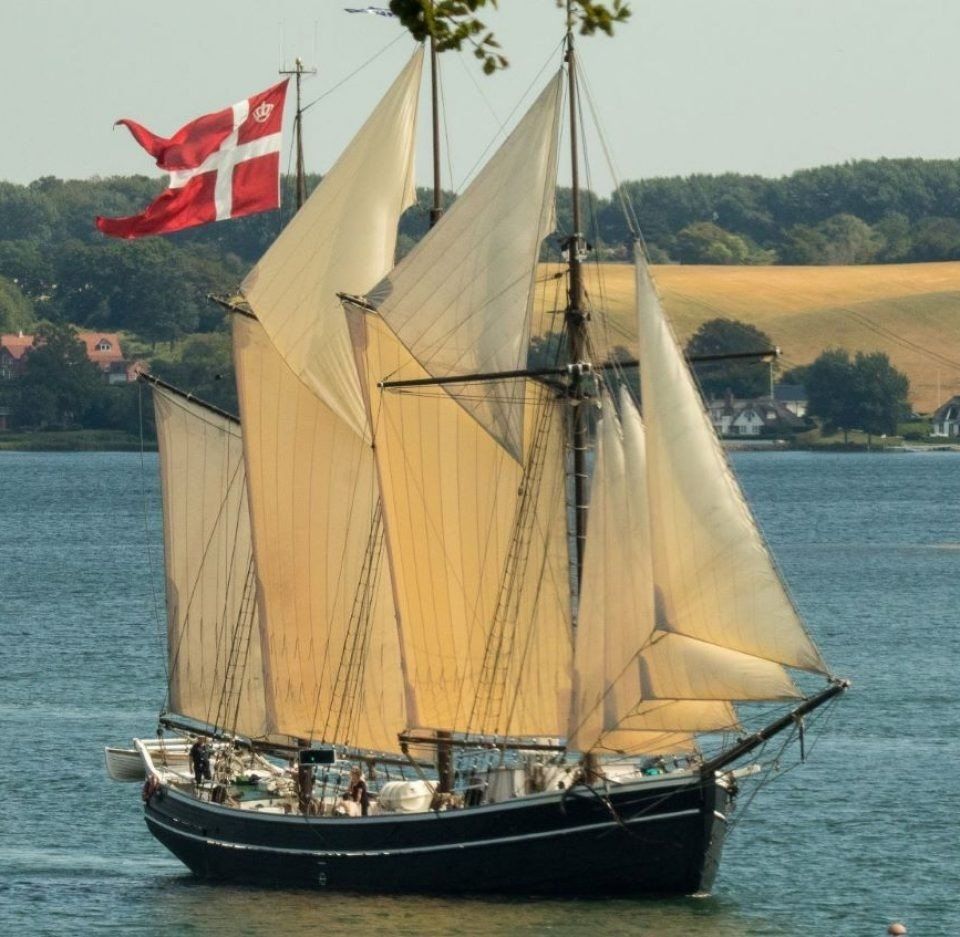 A sailboat with a red and white cross on the mast
