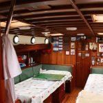 A living room on a boat with two beds and a table.