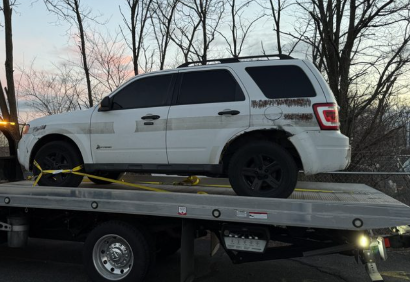 A white SUV on the back of a gray tow truck.