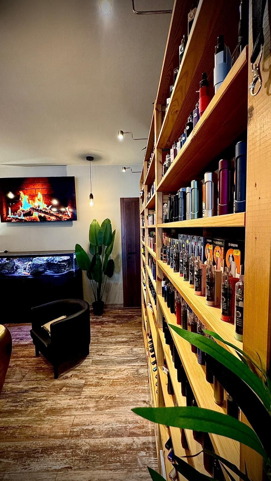 Interno di un negozio con scaffali pieni di prodotti, una TV, un acquario e una zona salotto.