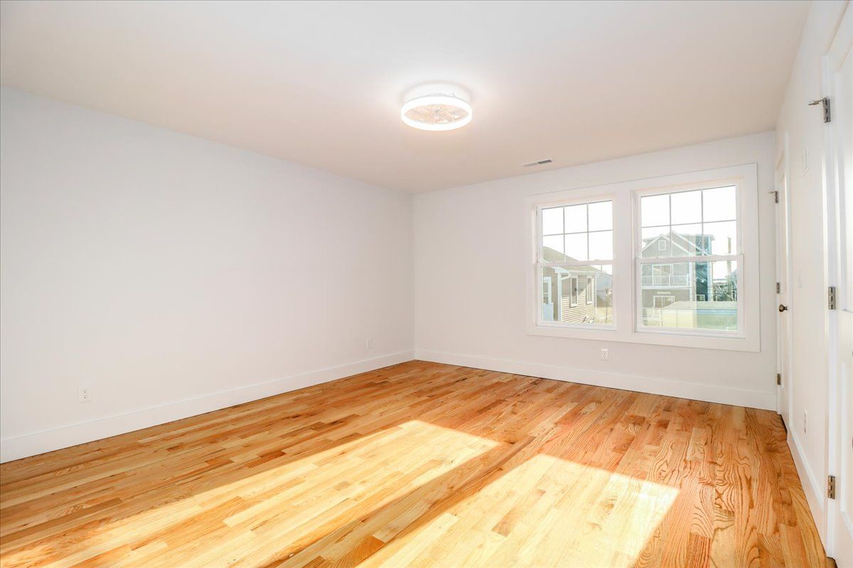 Empty room with hardwood floors, white walls, and a window.