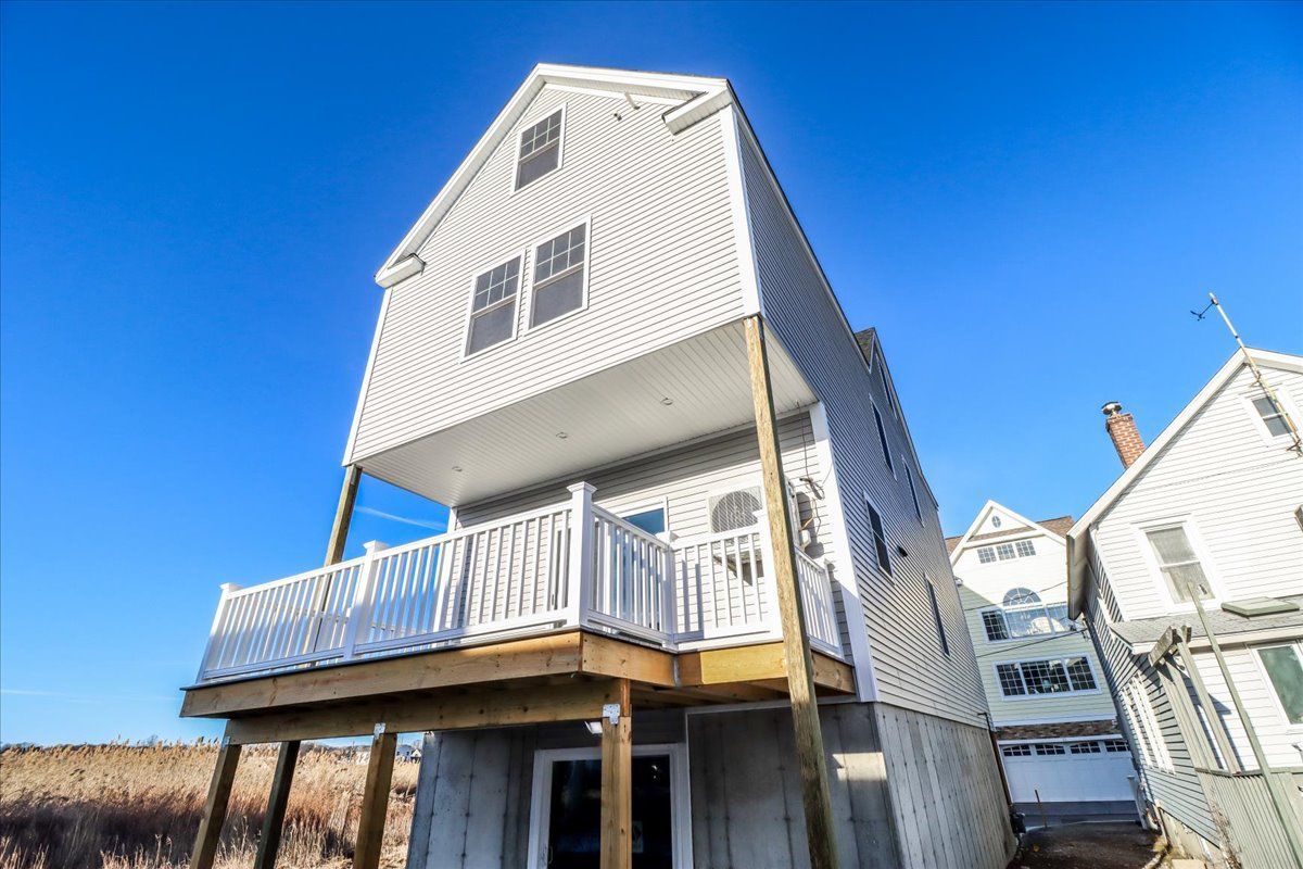 Two-story house with a balcony and white siding against a blue sky.
