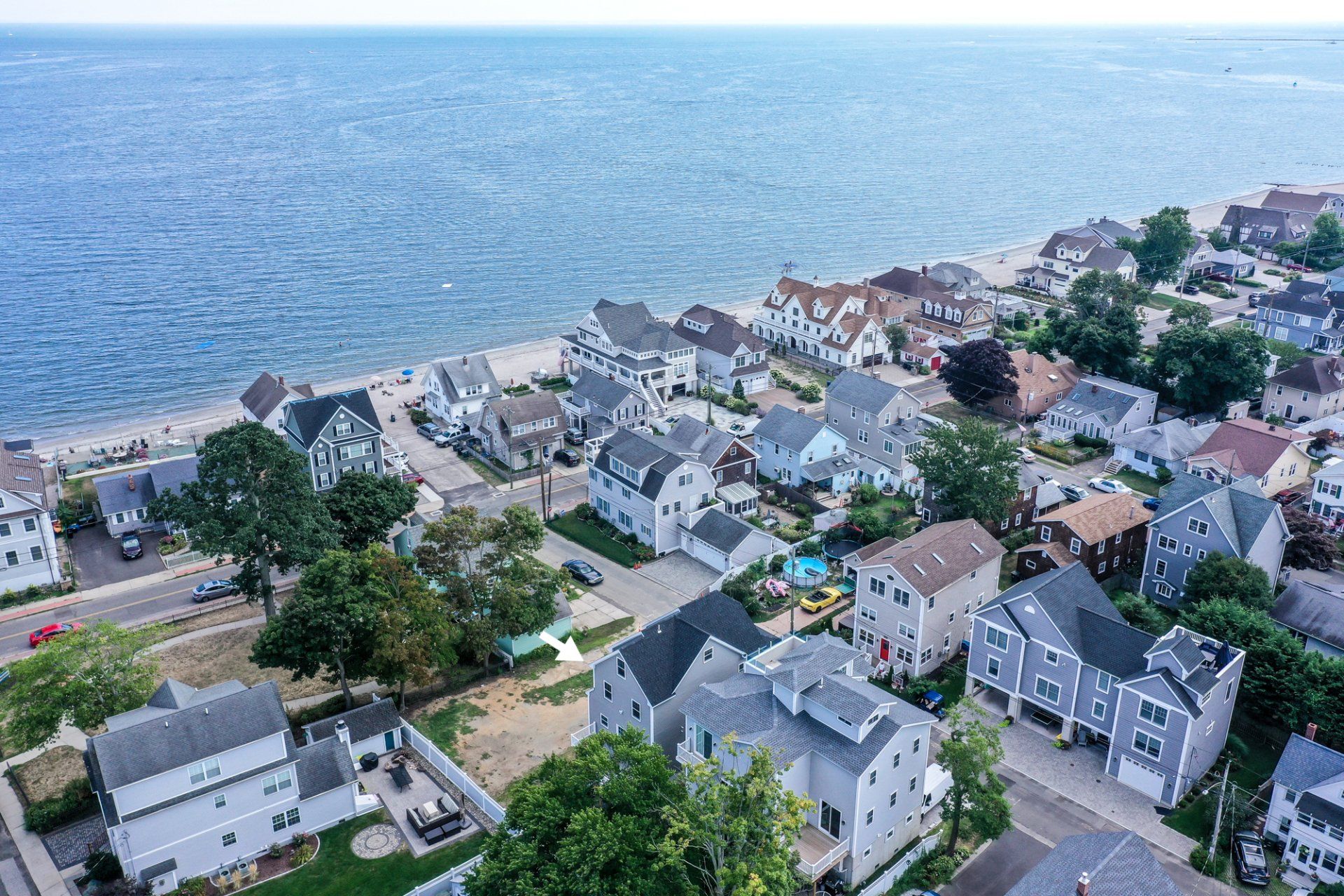 Aerial view of a coastal neighborhood with houses, a beach, and the ocean.