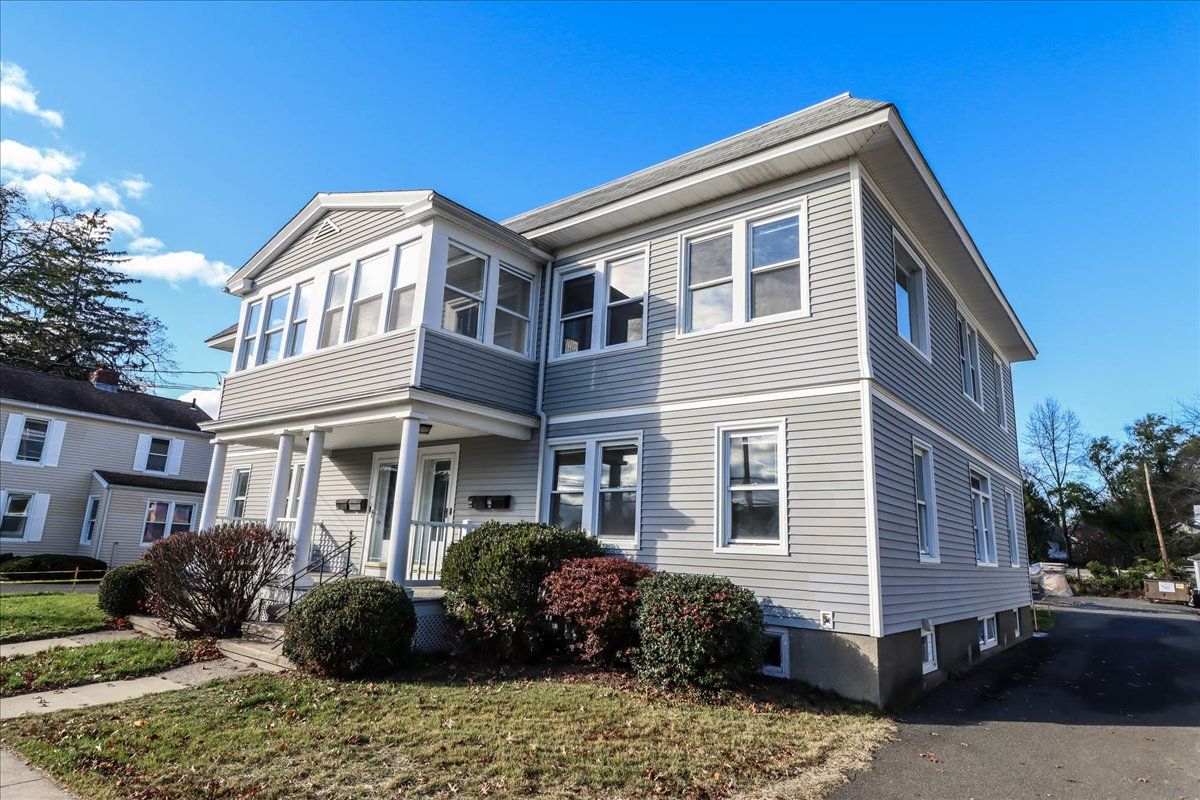 Gray multi-unit residential building with white trim, blue sky.