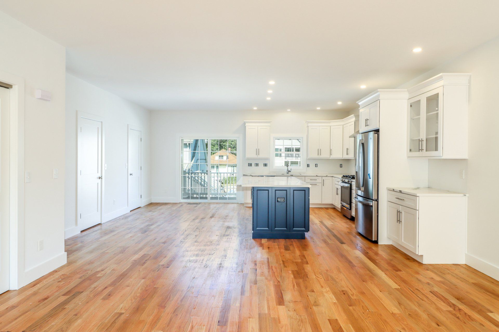 Open-concept kitchen and living area with hardwood floors, white cabinets, and a blue island.