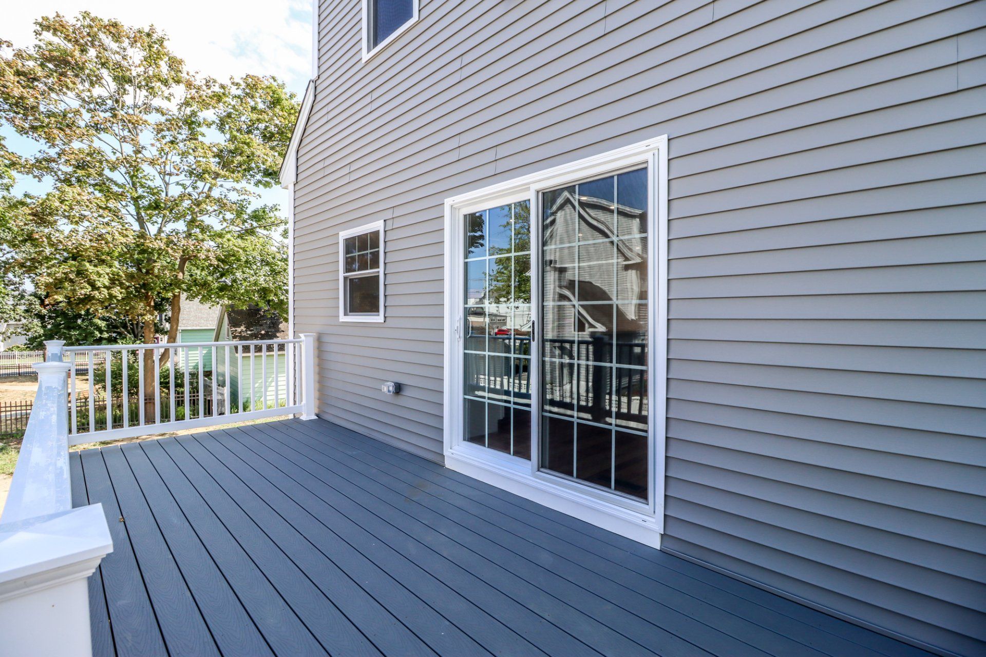 Gray house with a blue deck and sliding glass door.