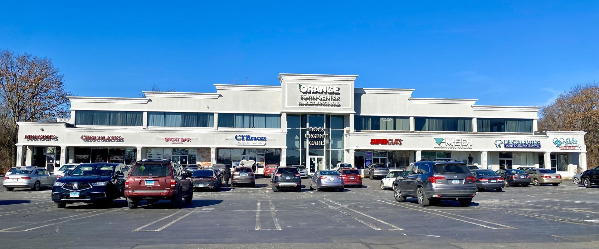 A strip mall with parked cars on a sunny day.