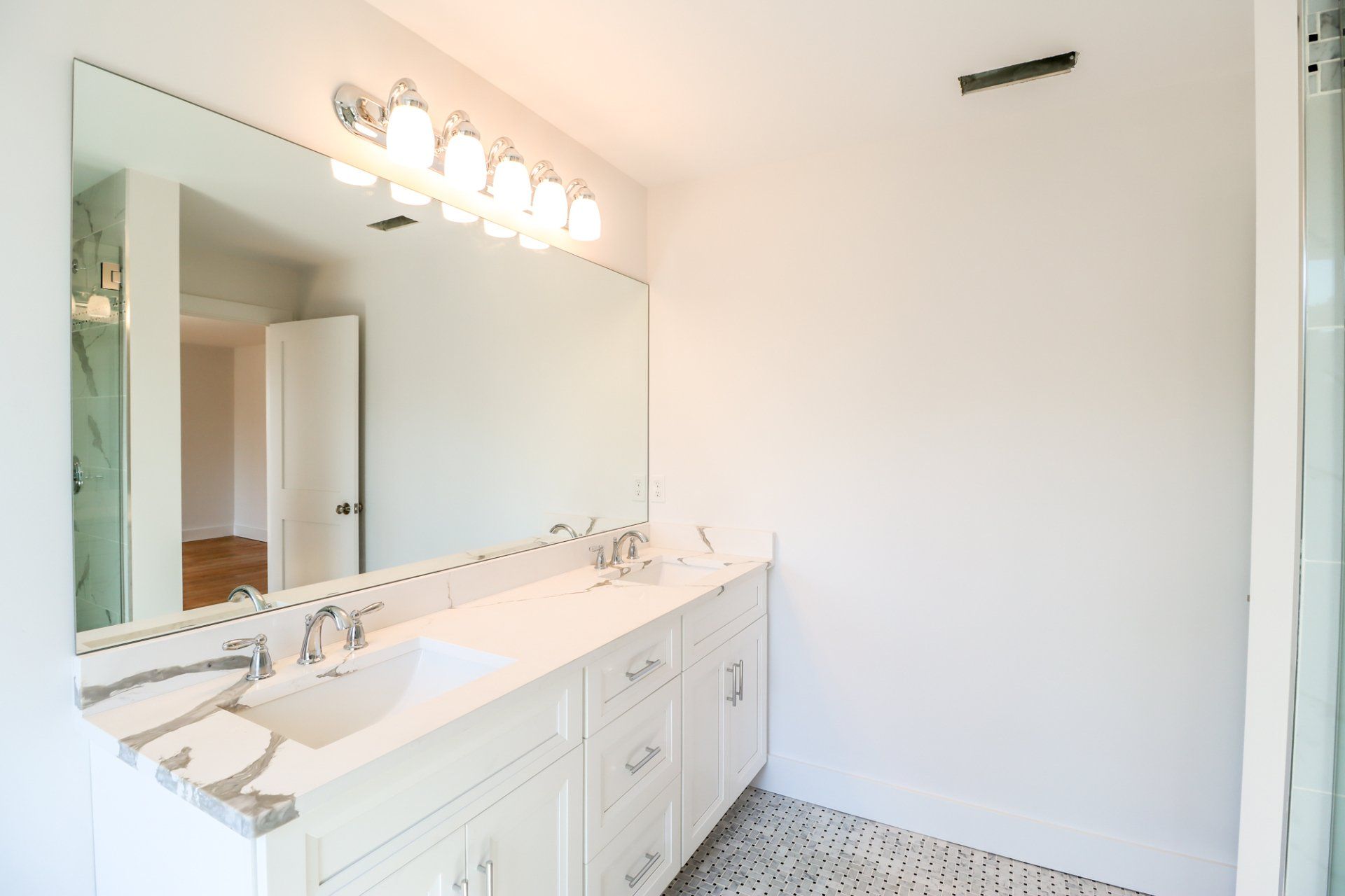 Bathroom with a white vanity, large mirror, and overhead lights.