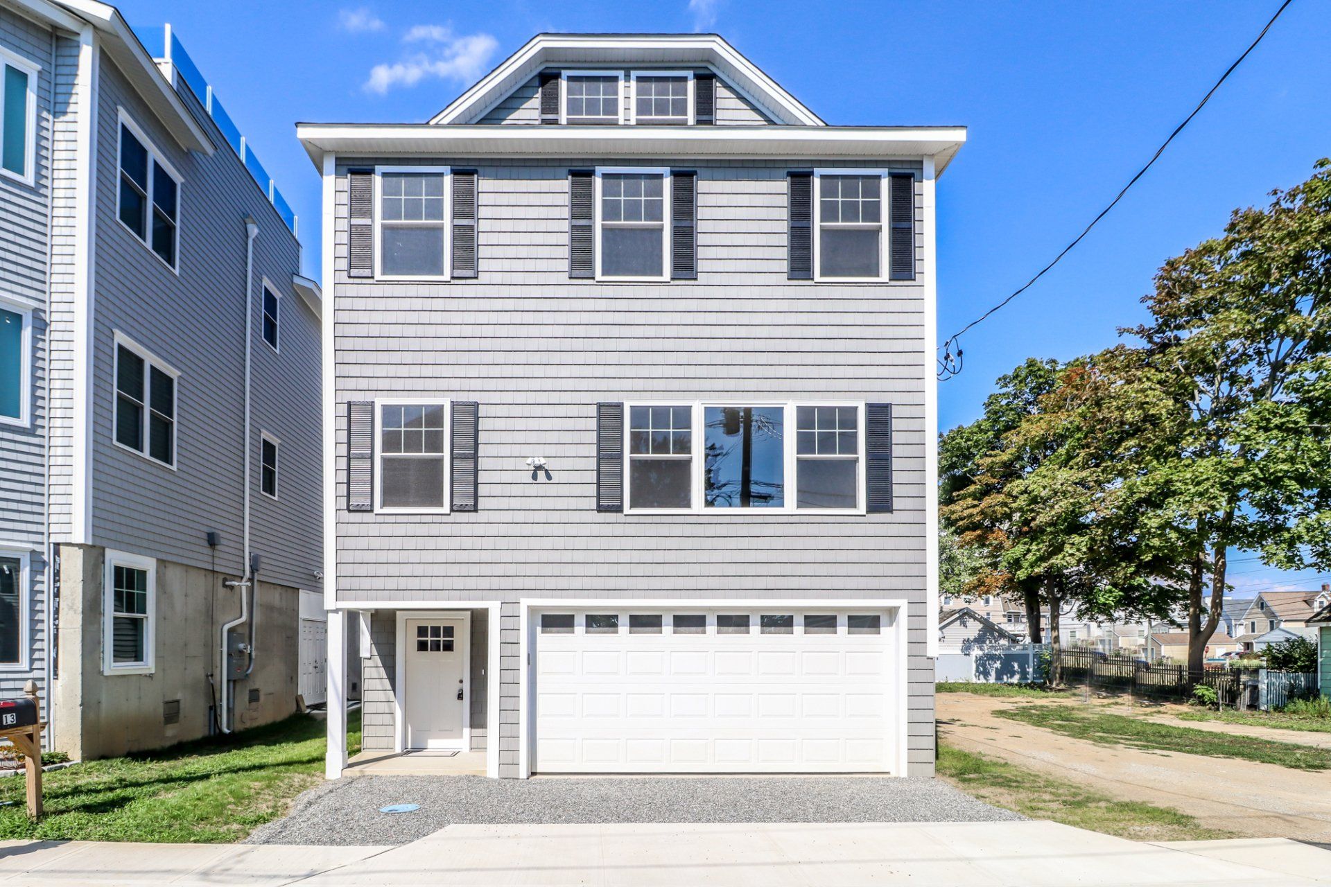 Gray three-story house with a garage and black shutters.