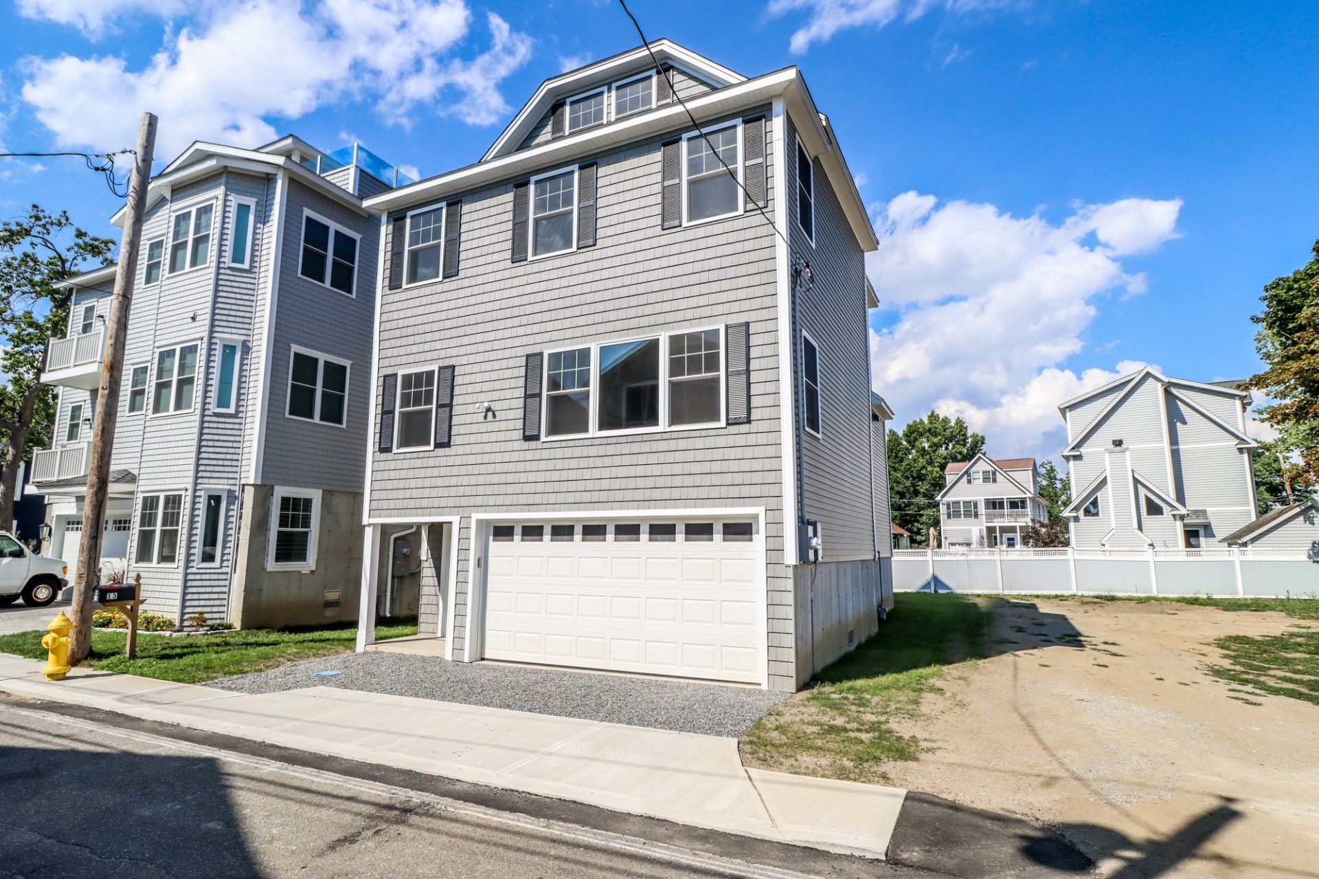 Gray house with white garage door and blue sky.