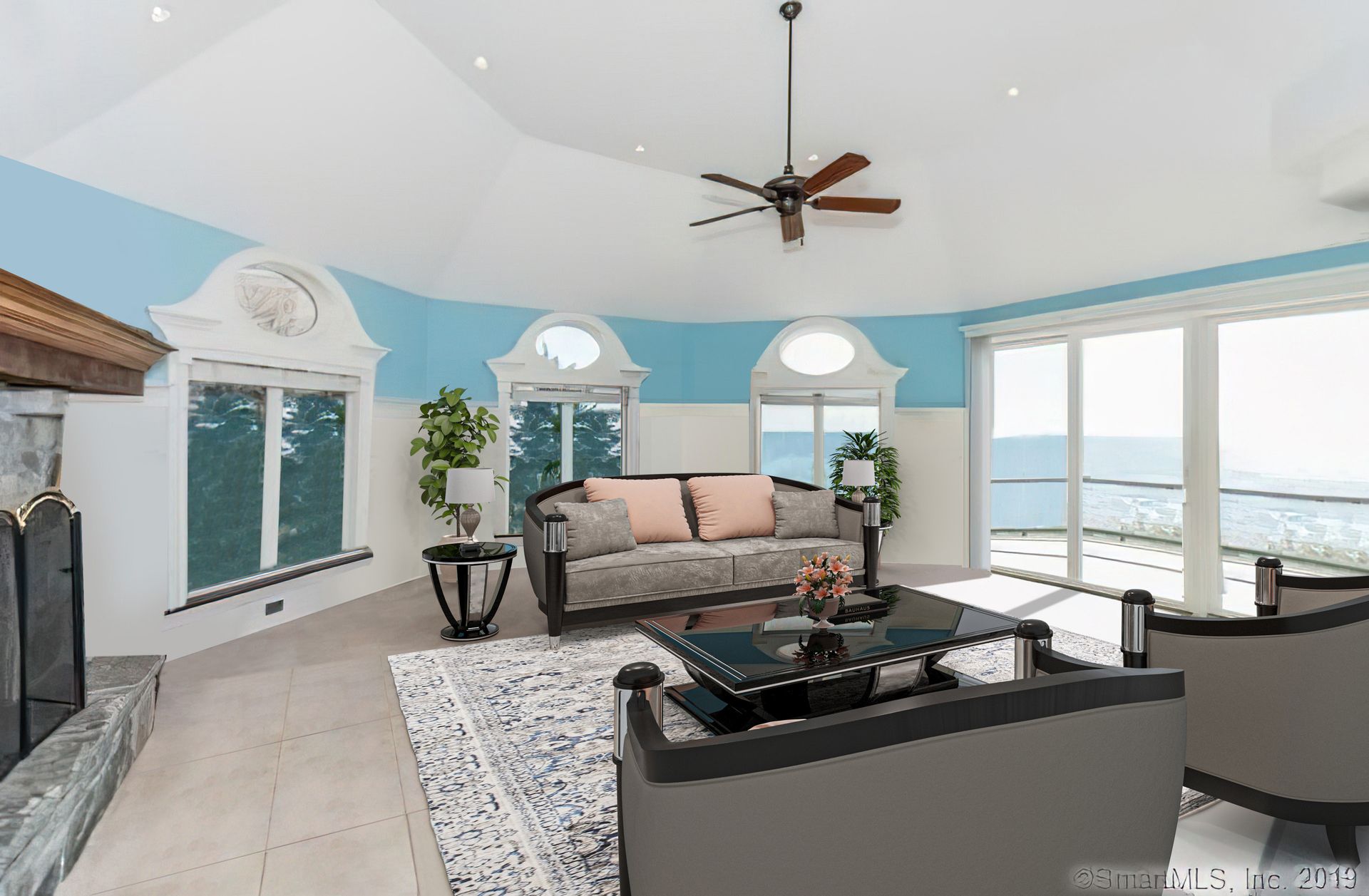 Spacious living room with large windows, blue accent walls, and gray furniture.