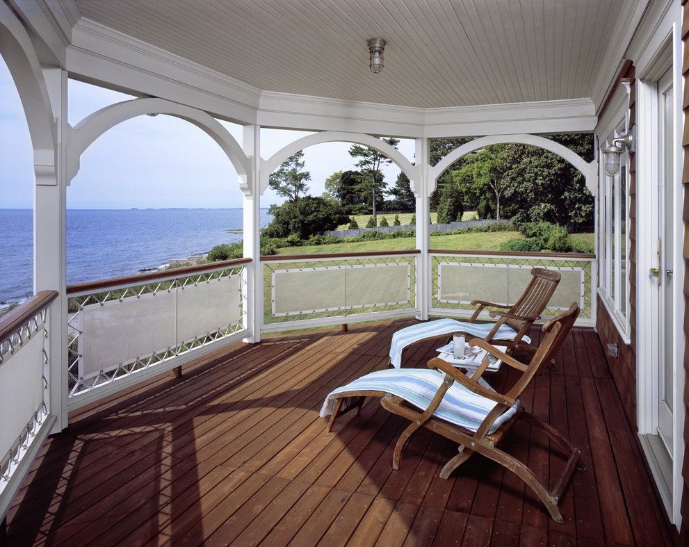 Wooden deck with ocean view, two lounge chairs, white trim, and a blue and white striped towel.