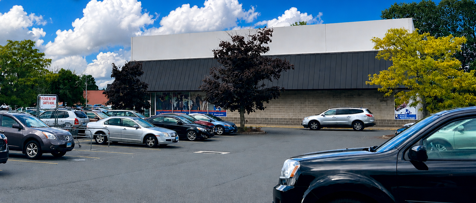 Shopping center exterior with cars in the parking lot. Stores include Ocean State Job Lot and Goodwill on a sunny day.