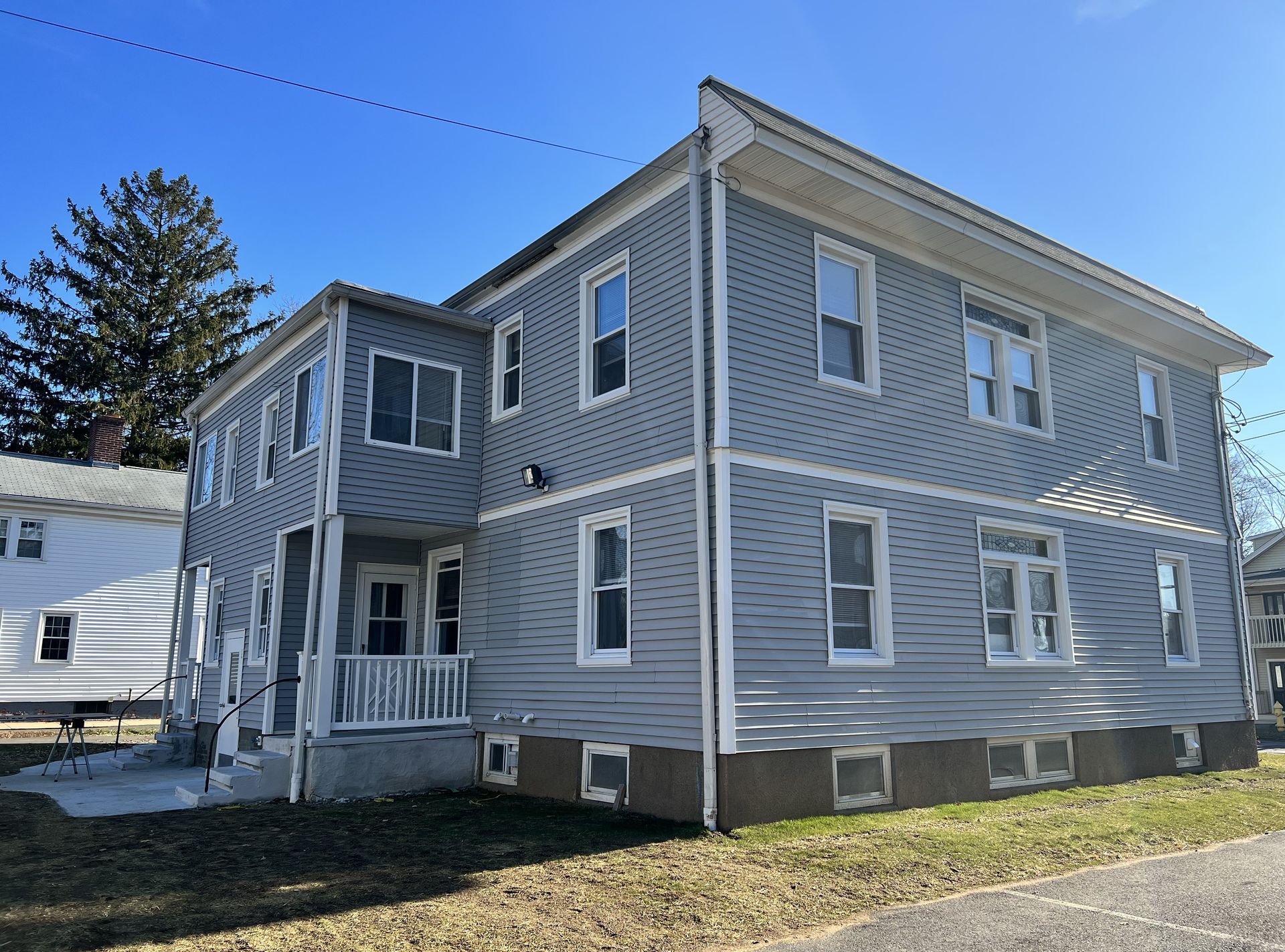 Two-story gray building with white trim under a clear, blue sky.