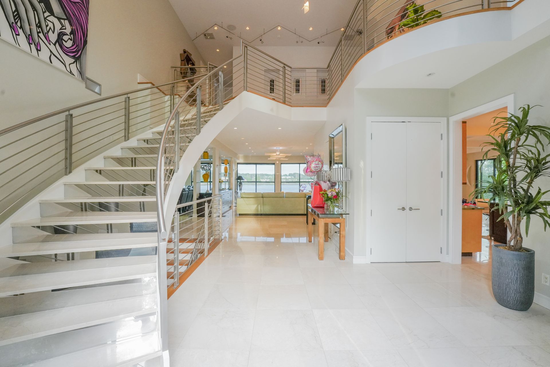 Grand foyer with a staircase, white floors, and a view of the water.