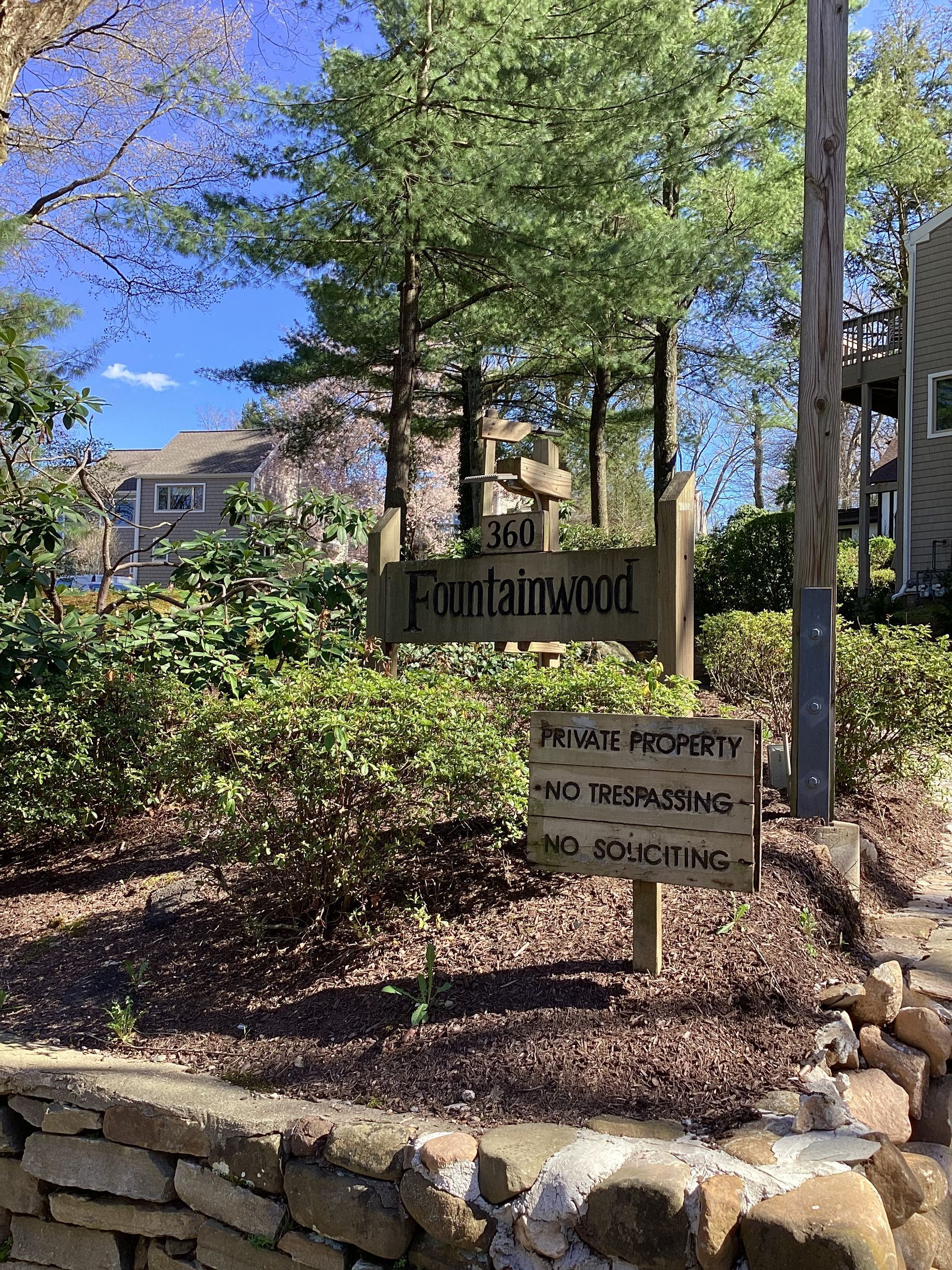 Sign for Fountainwood apartments, wooden sign with text. Below, a smaller sign that reads: