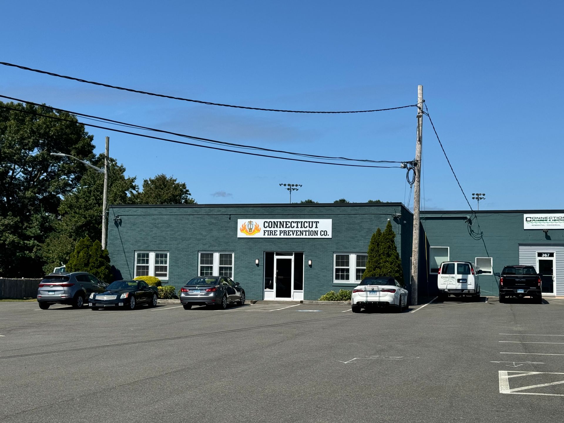 Exterior of commercial building, teal-painted brick, cars parked in front, clear blue sky.