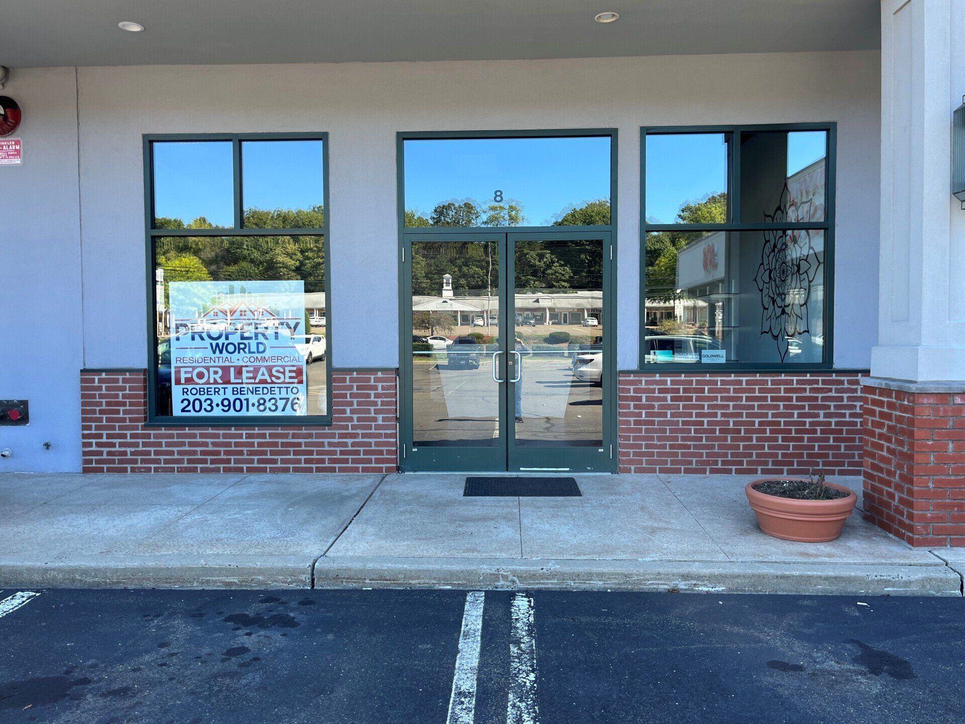 Storefront with glass doors and windows, brick accents, and a sign in the window.
