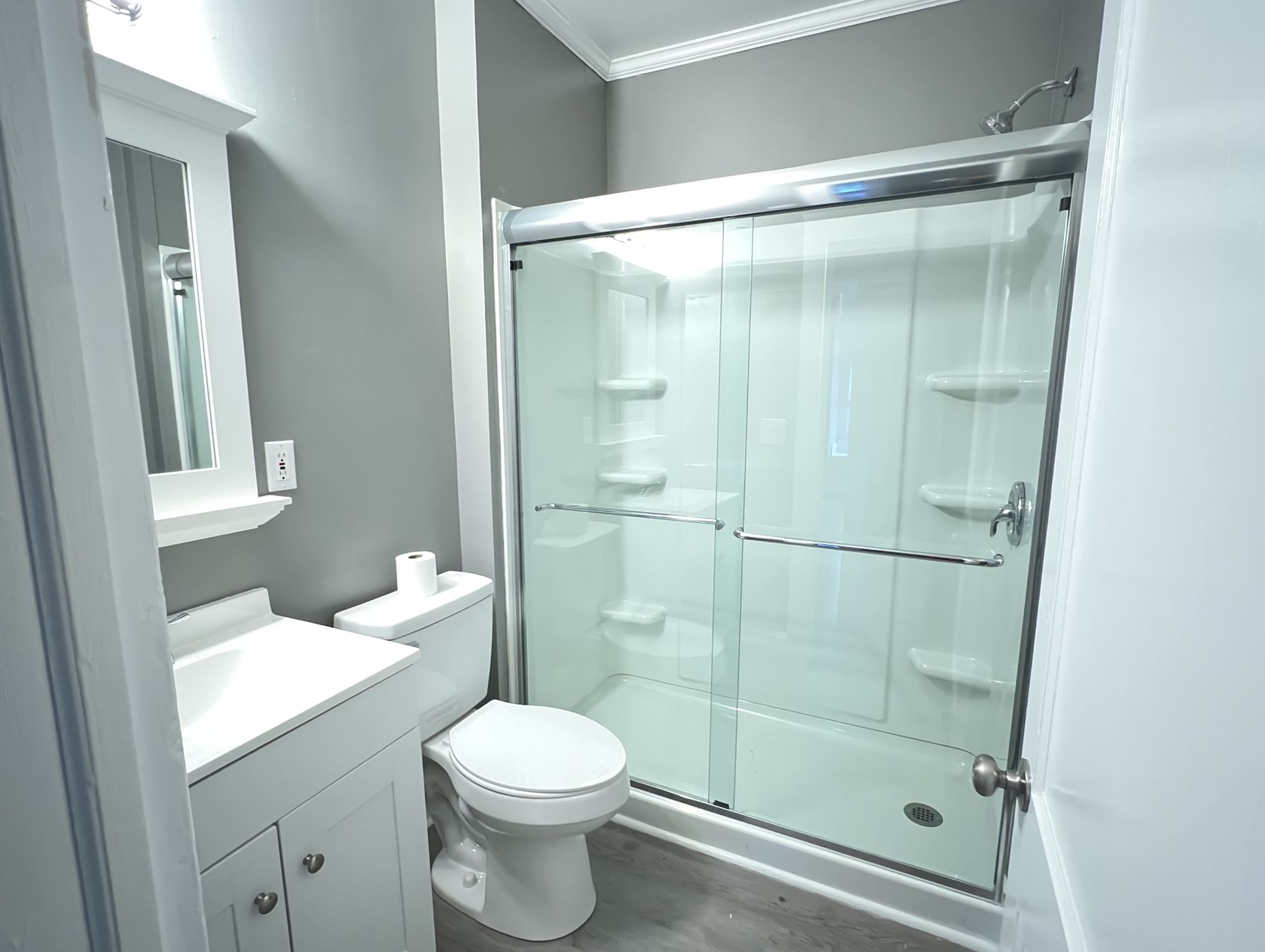 Bathroom with white vanity, toilet, and shower/tub combo. Gray walls and flooring.