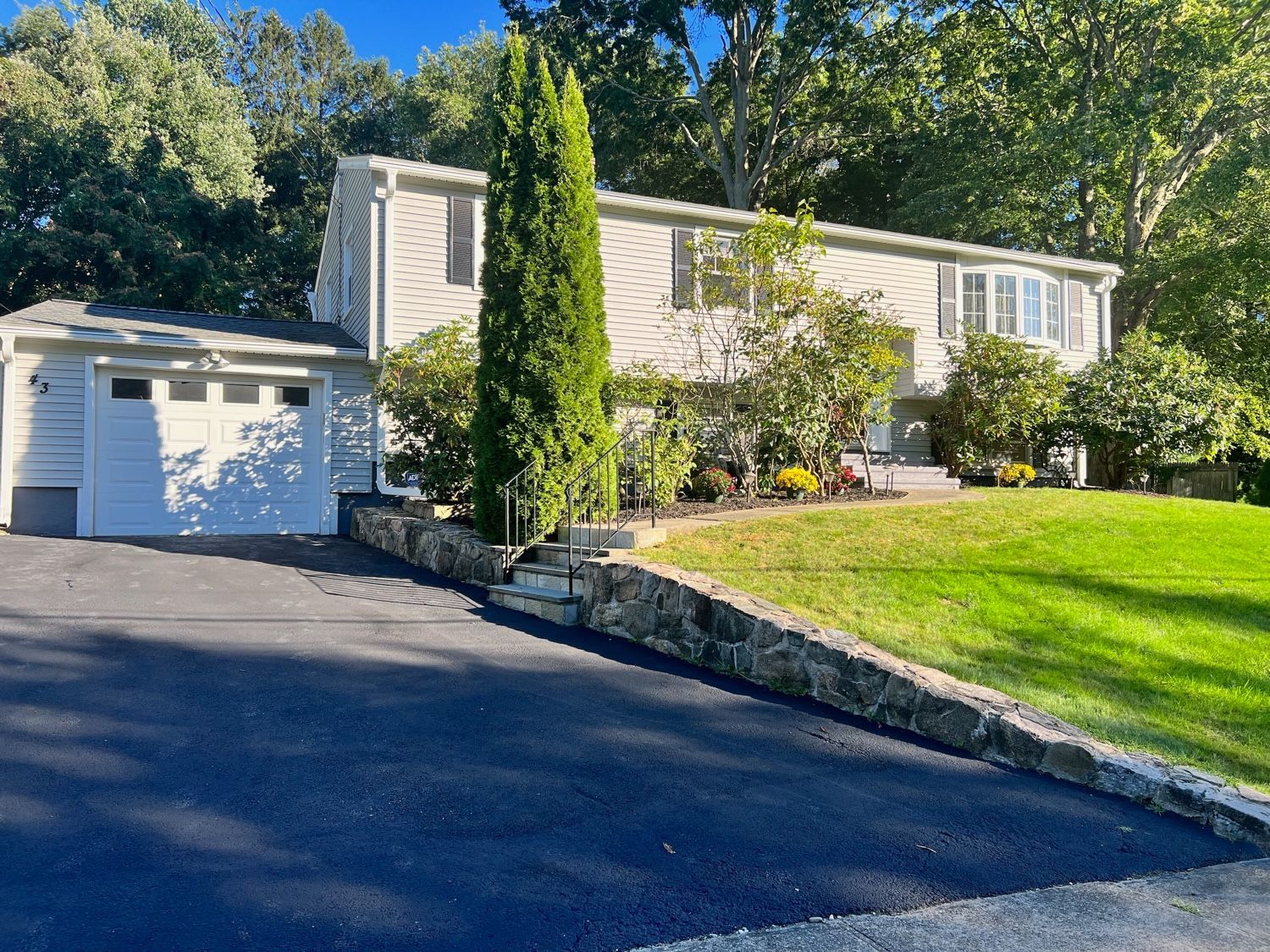Suburban home with attached garage, landscaped yard, and asphalt driveway.