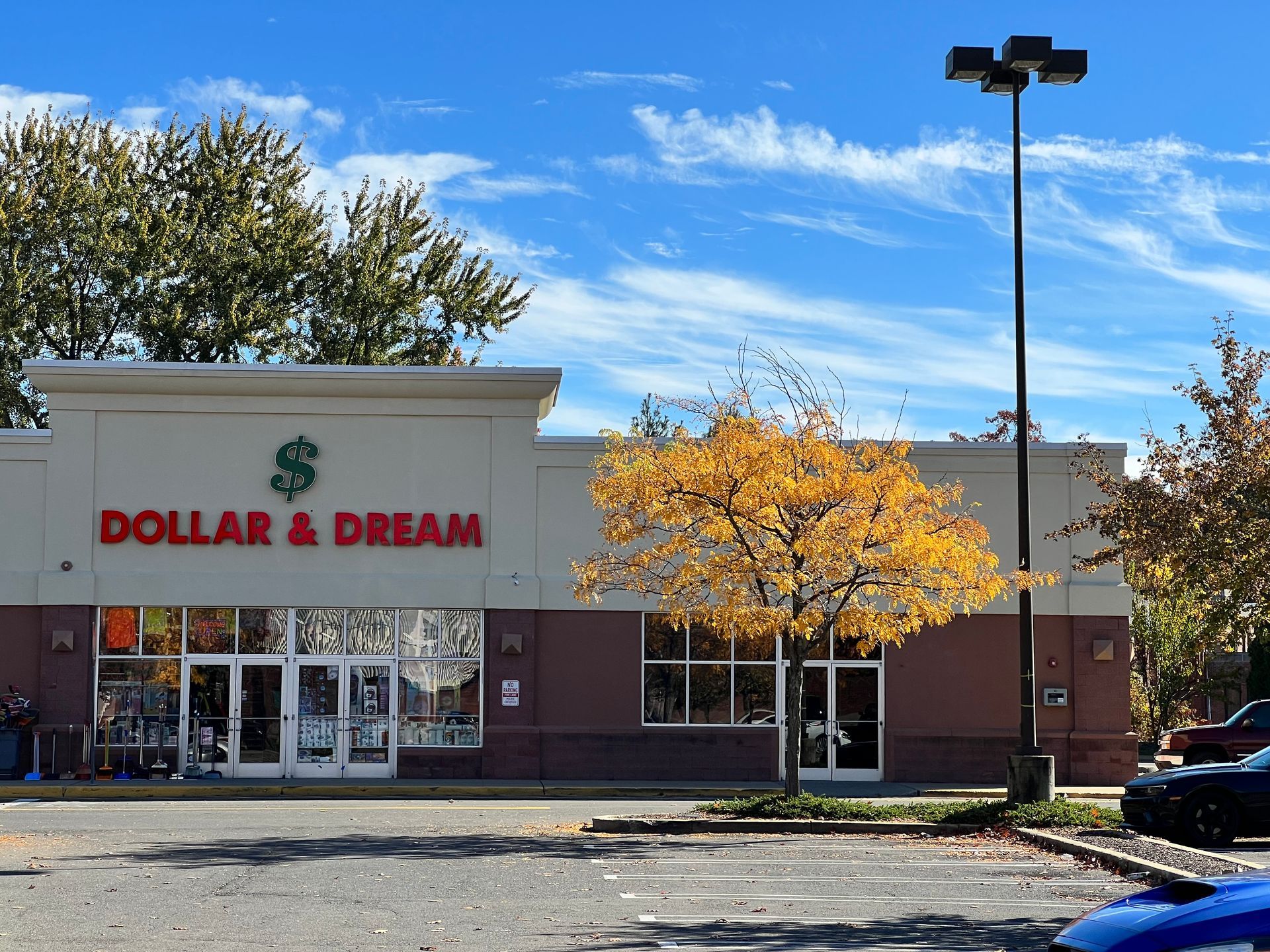 Dollar & Dream store front with a sign and parking lot on a sunny day.