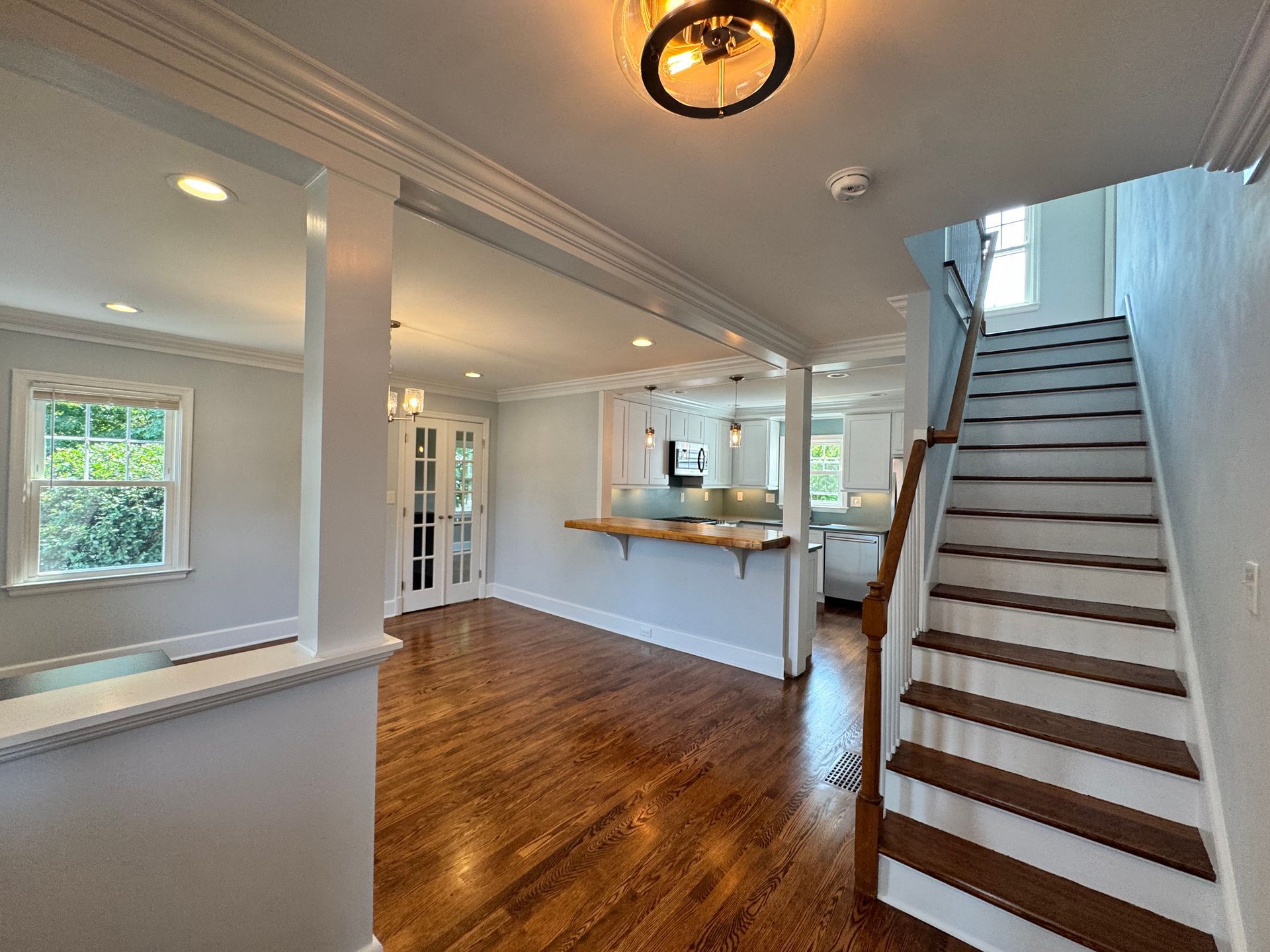 Interior view: Living area with hardwood floors, staircase, and partial kitchen visible.