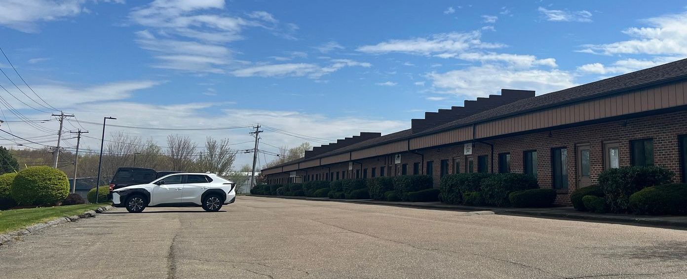 A white car parked in front of a long, low building under a blue sky.