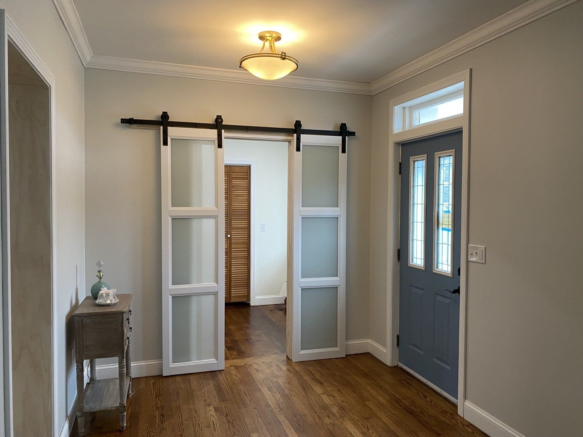 Hallway with frosted glass sliding doors, wood floors, and a blue front door.
