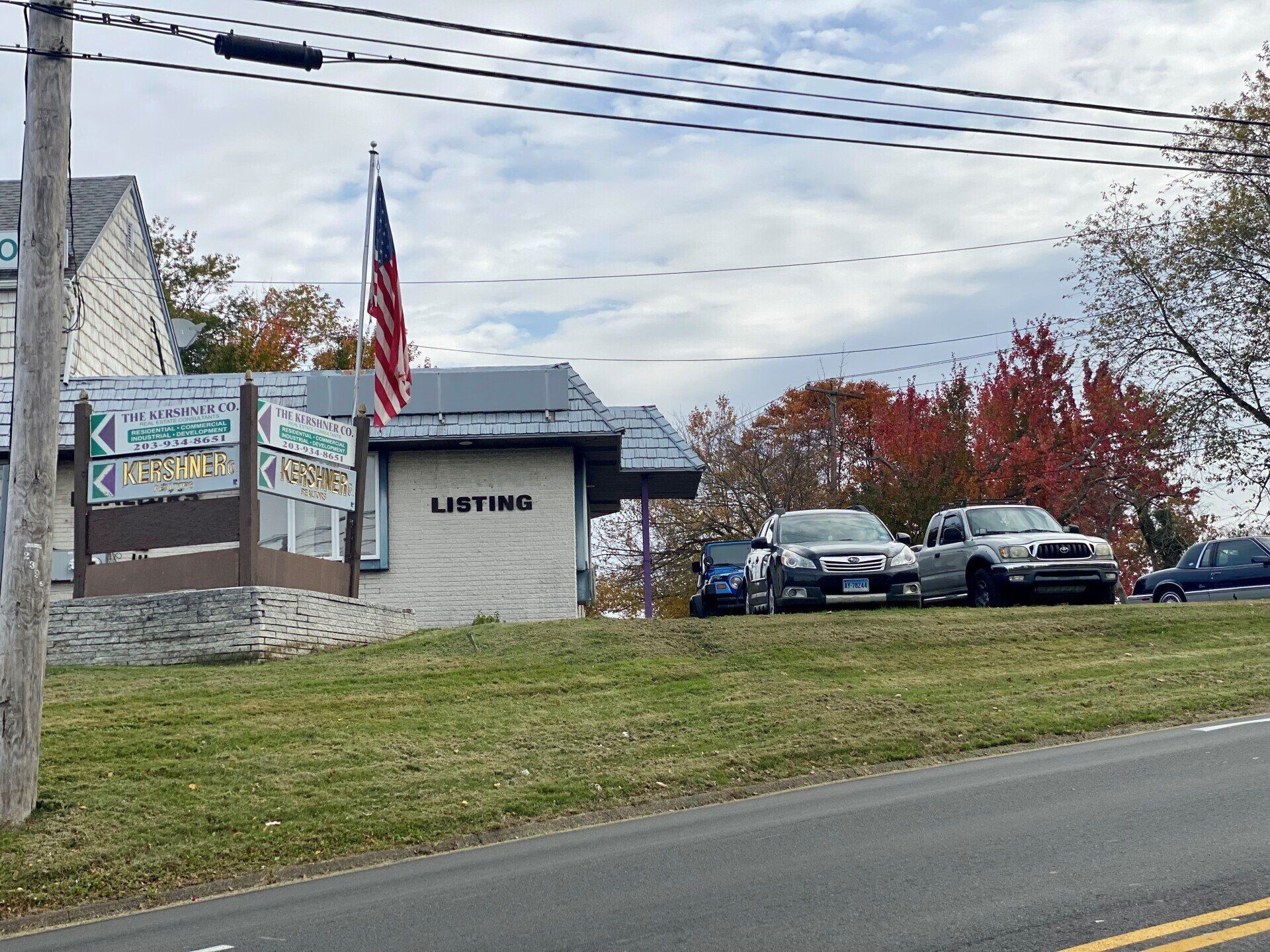 A building with a sign and an American flag; cars parked in front.