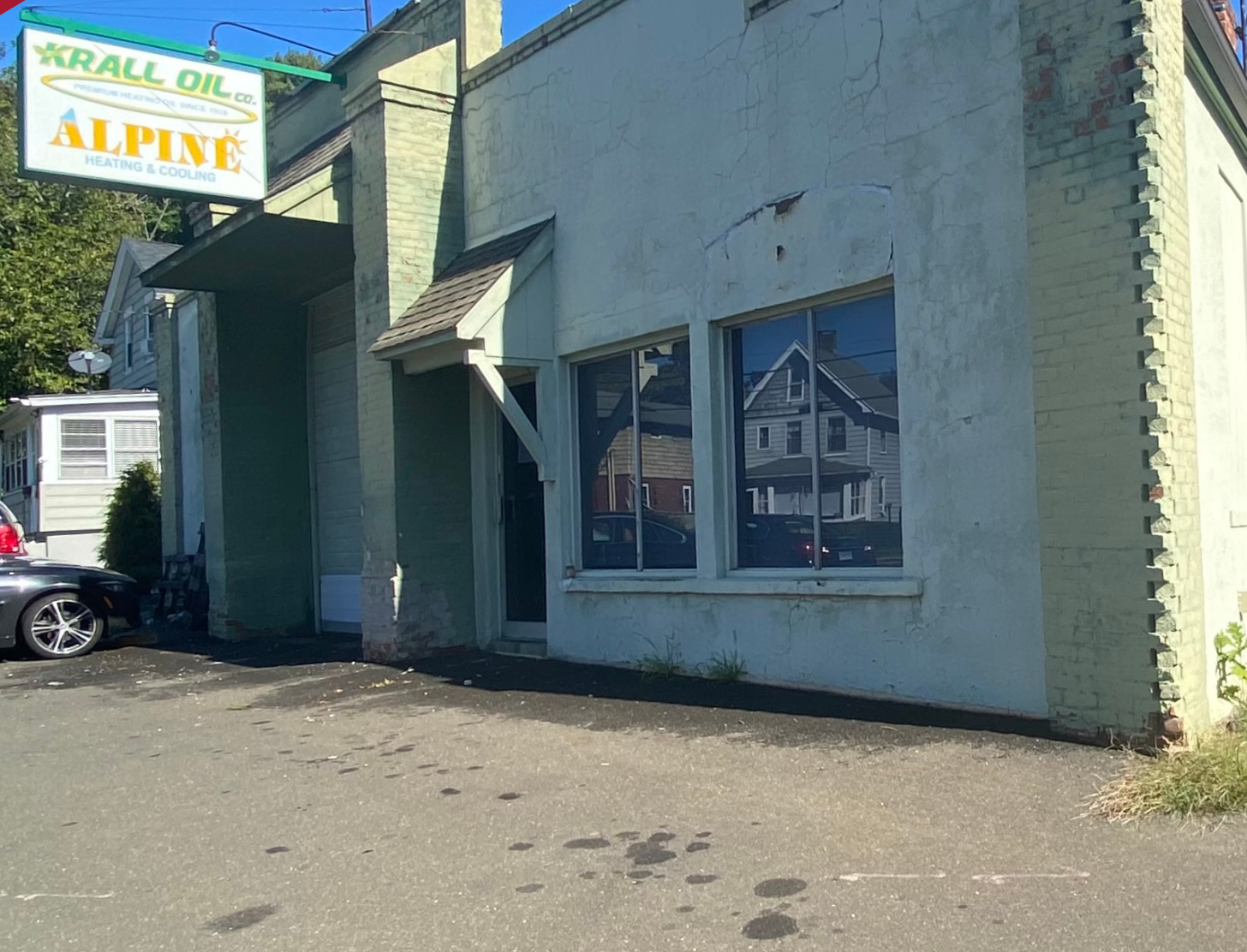 Green-painted brick building with Krall Oil and Alpine sign; a car parked in front.