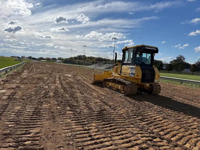 Yellow bulldozer grading a dirt road under a cloudy sky on a construction site