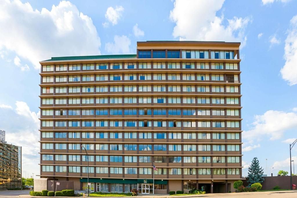 Tall beige office building with many windows under a blue sky with clouds