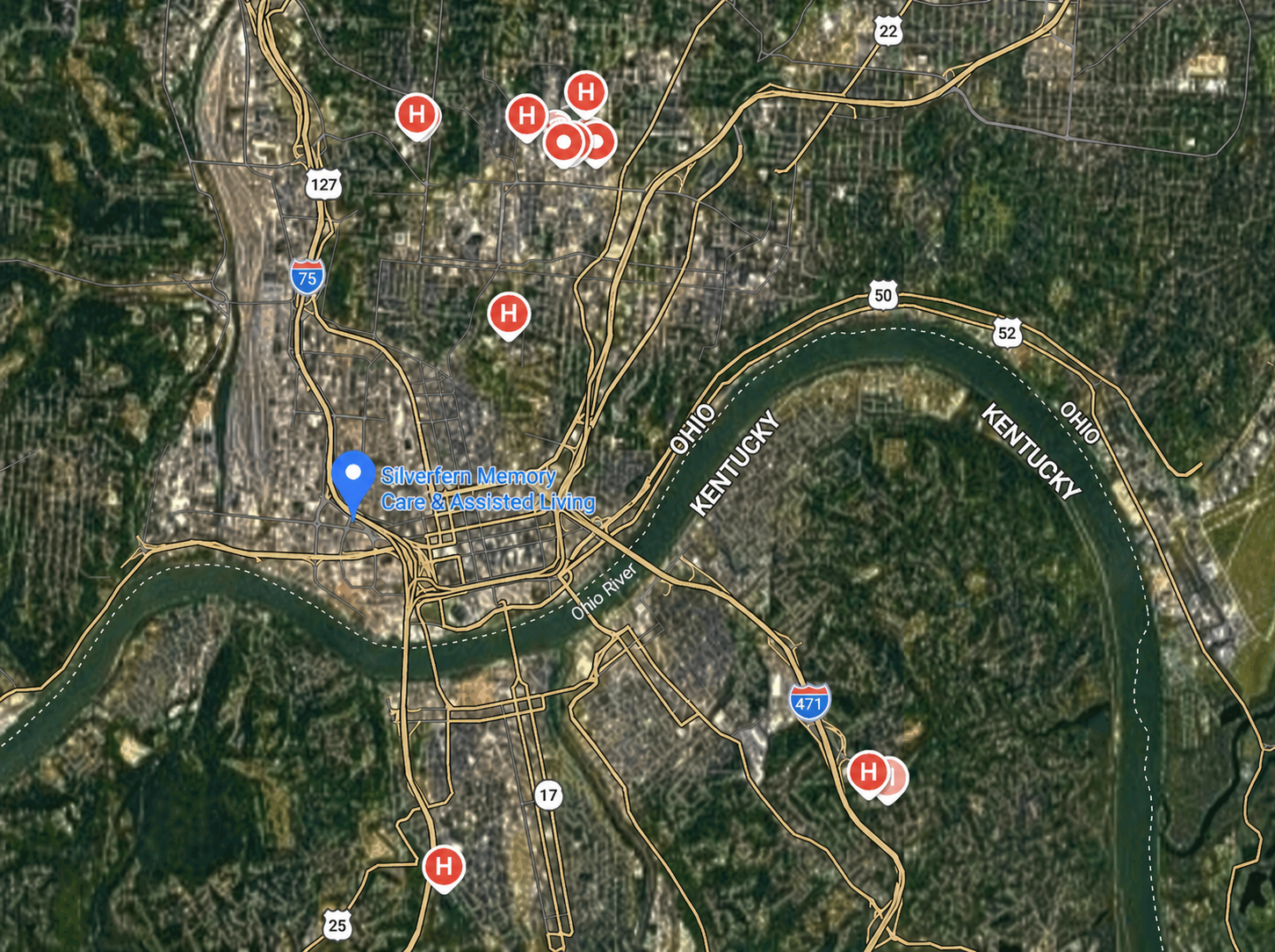 Satellite map with multiple red location pins around a river bend and one blue marker on a city street map