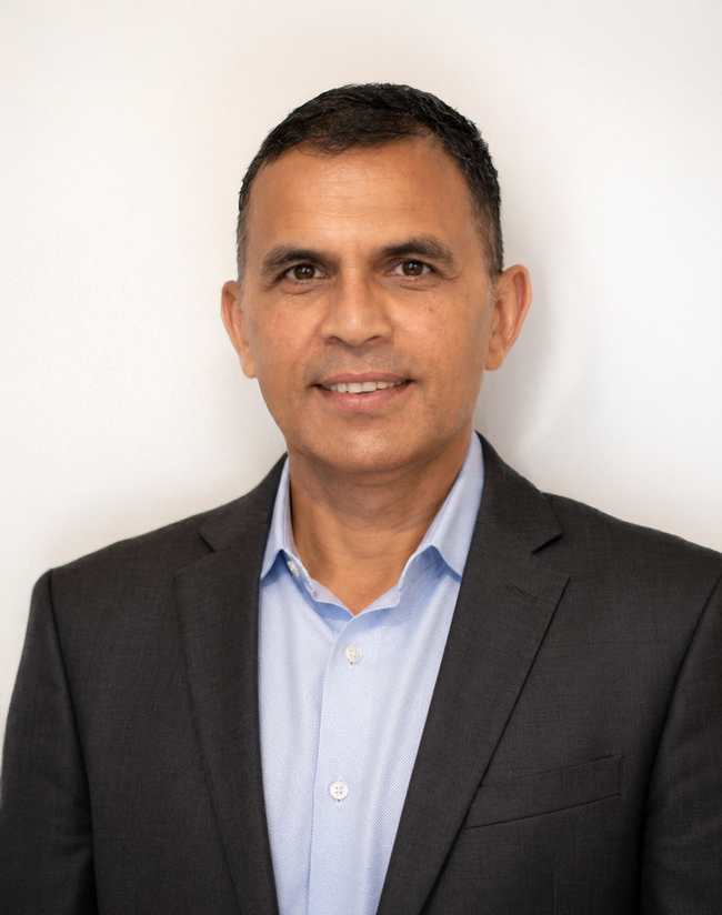 Portrait of a man in a dark blazer and light blue shirt against a plain white background
