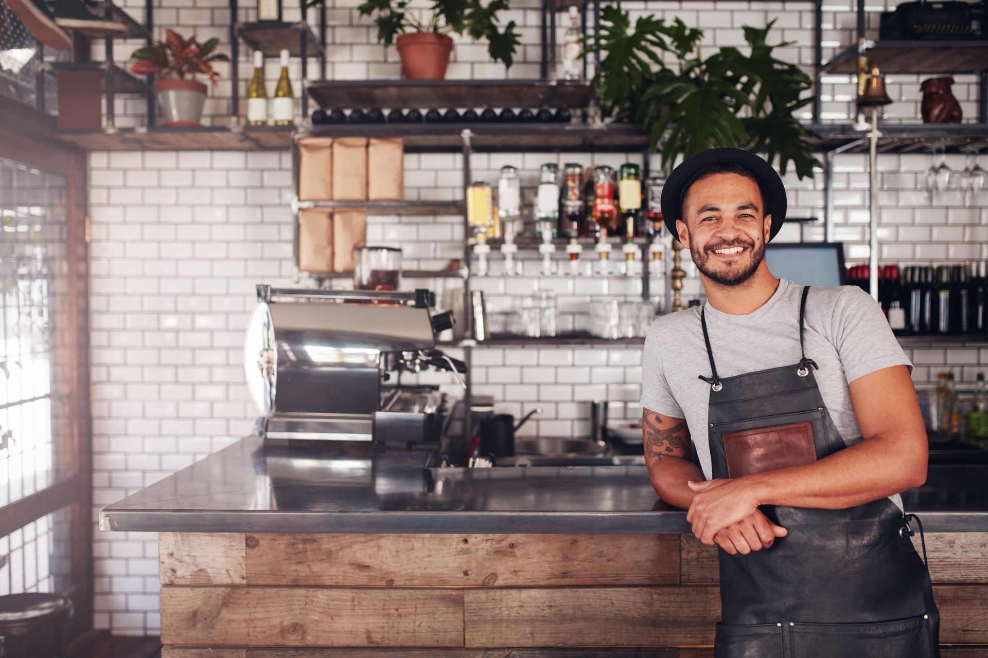 a man in an apron is standing in front of a counter in a restaurant .