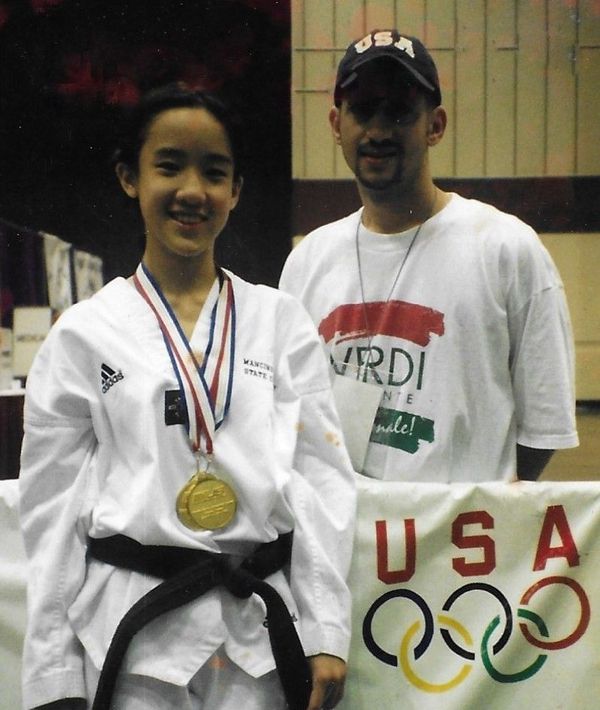 A man and a girl pose in front of a US Olympics sign. Mancino Academy Martial Arts