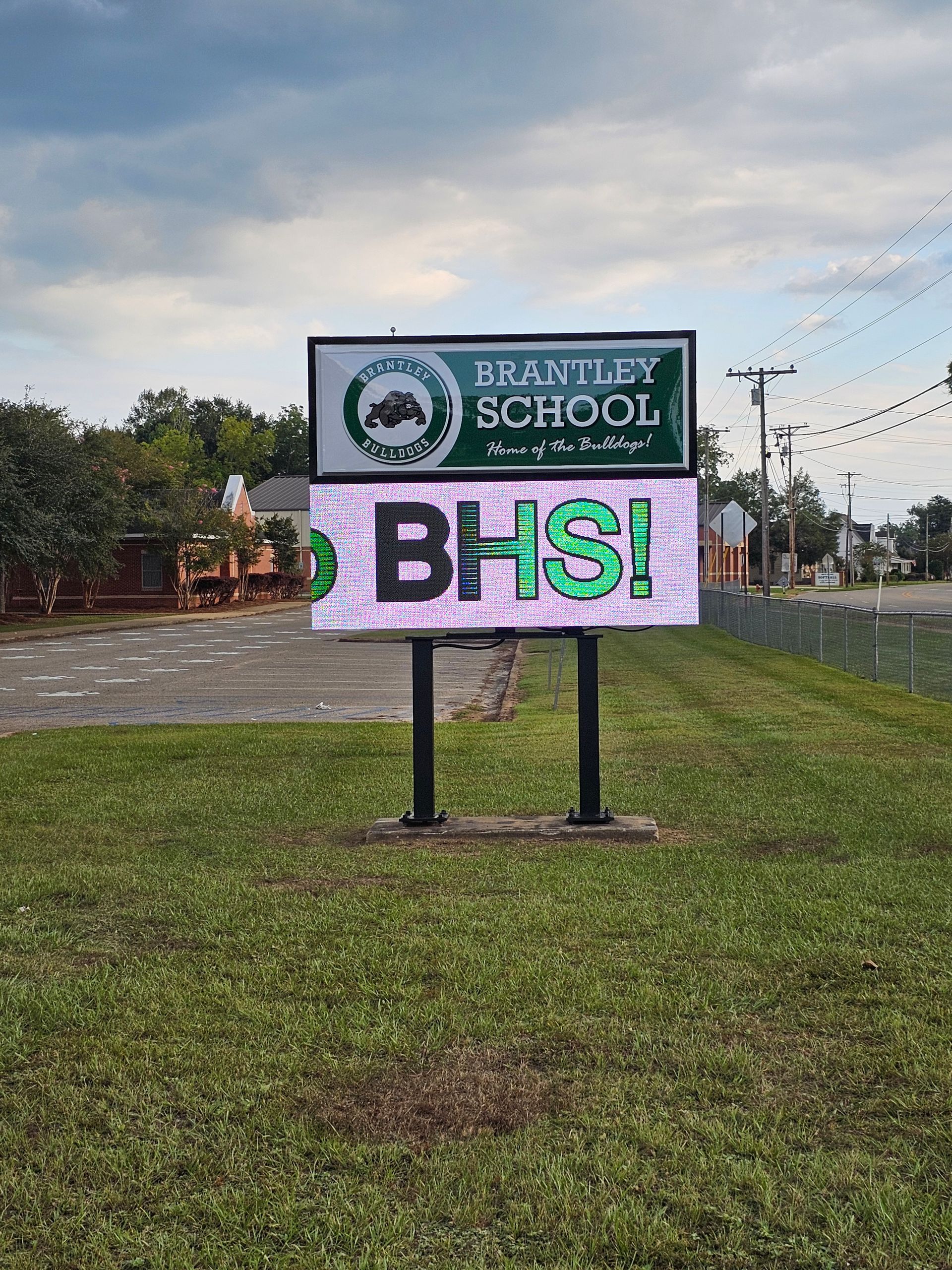 A billboard for branley school is sitting on top of a lush green field.