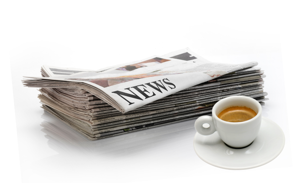 Una pila di giornali accanto a una tazza di caffè su un piattino.