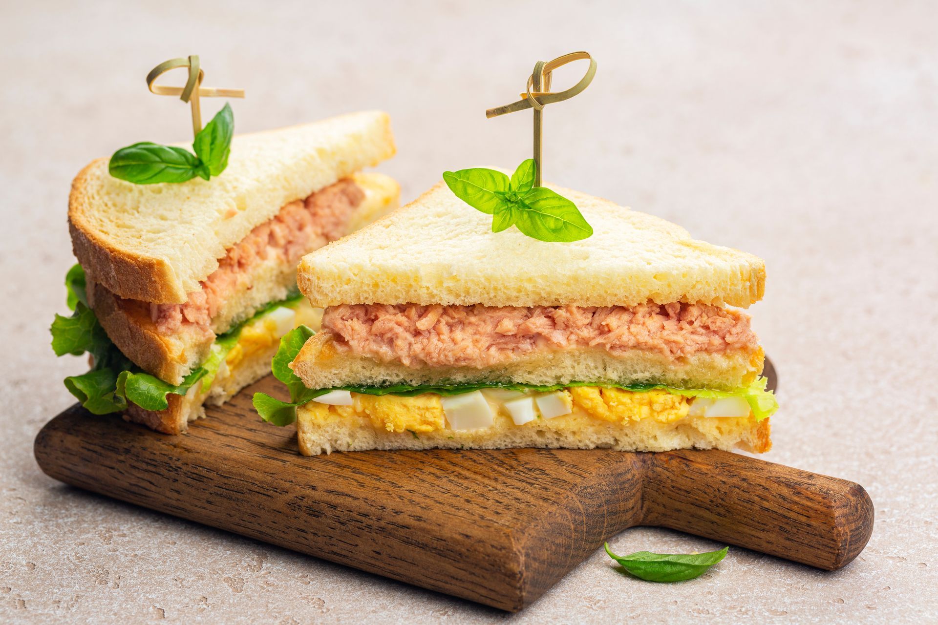 Due panini vengono tagliati a metà su un tagliere di legno.
