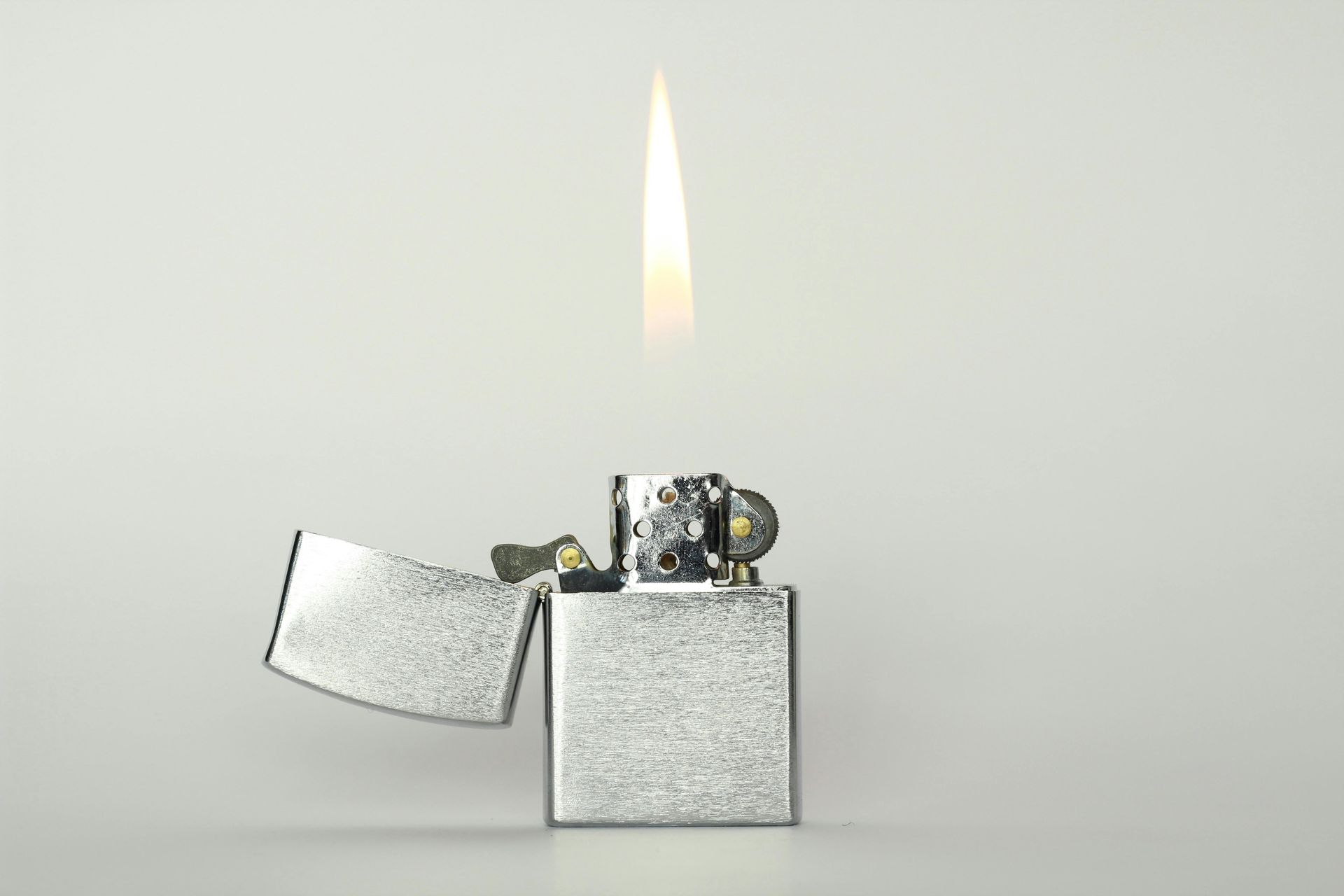 Un accendino Zippo argentato da cui esce una fiamma
