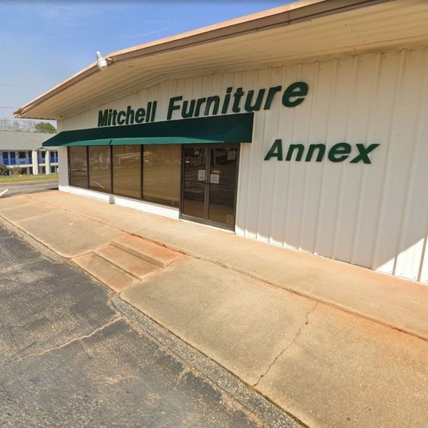 Mitchell Furniture Annex storefront with green awning and beige exterior under a clear sky