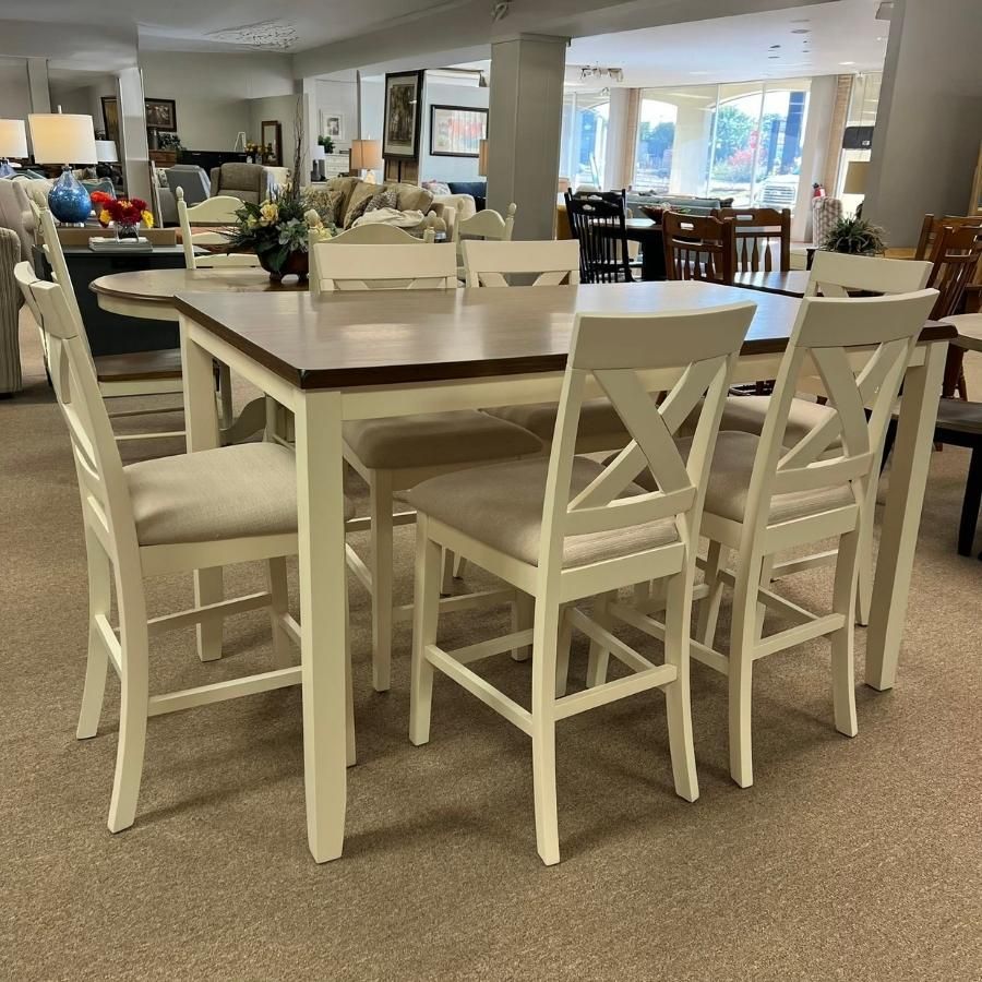 White dining table with matching chairs in a bright showroom or open living space.