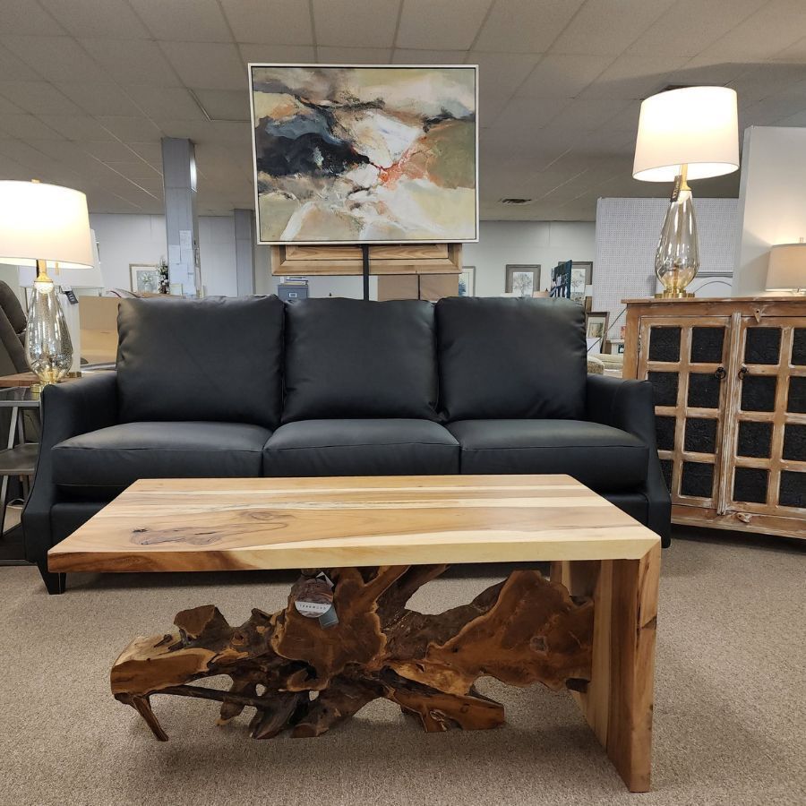 Showroom living room with black sofa, wood coffee table, lamps, and abstract wall art