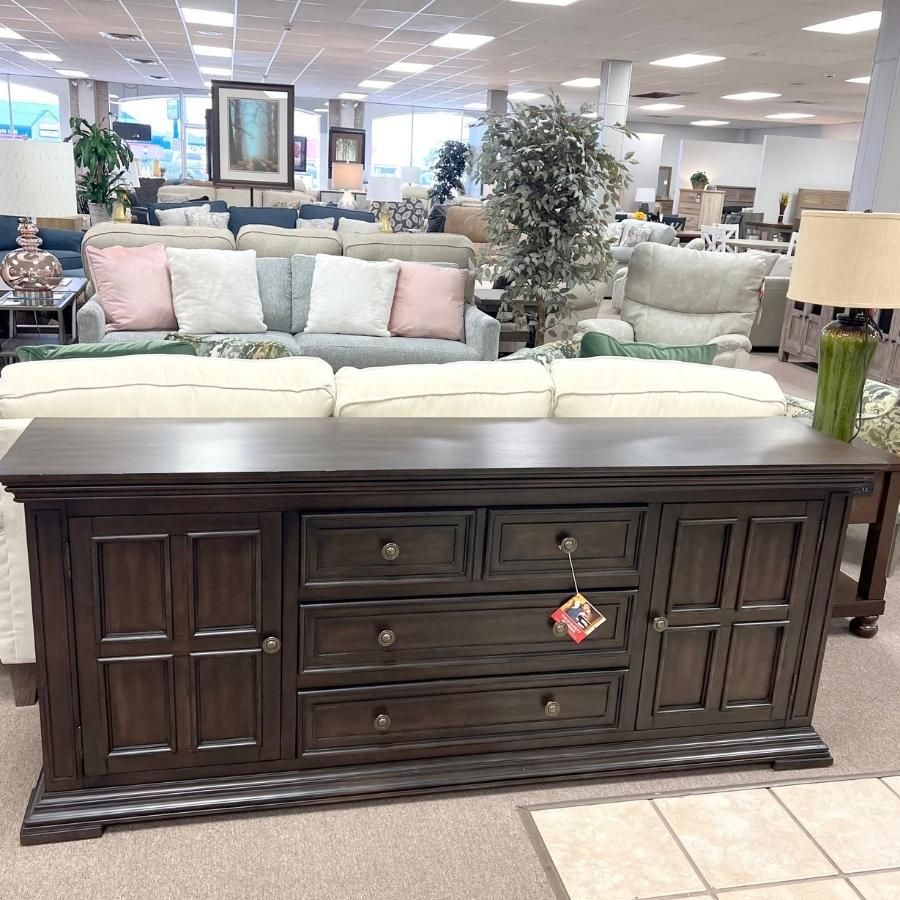 Dark wood sideboard in a furniture showroom with sofas and lamps in the background