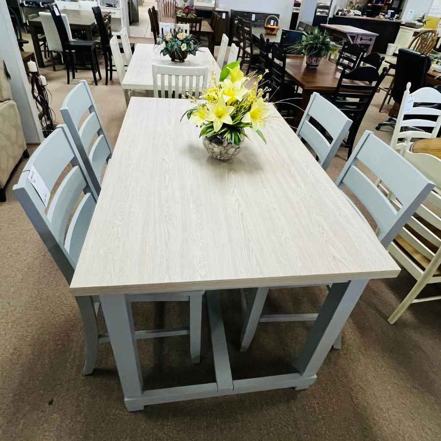 Dining table with light wood top, gray chairs, and a yellow floral centerpiece in a showroom