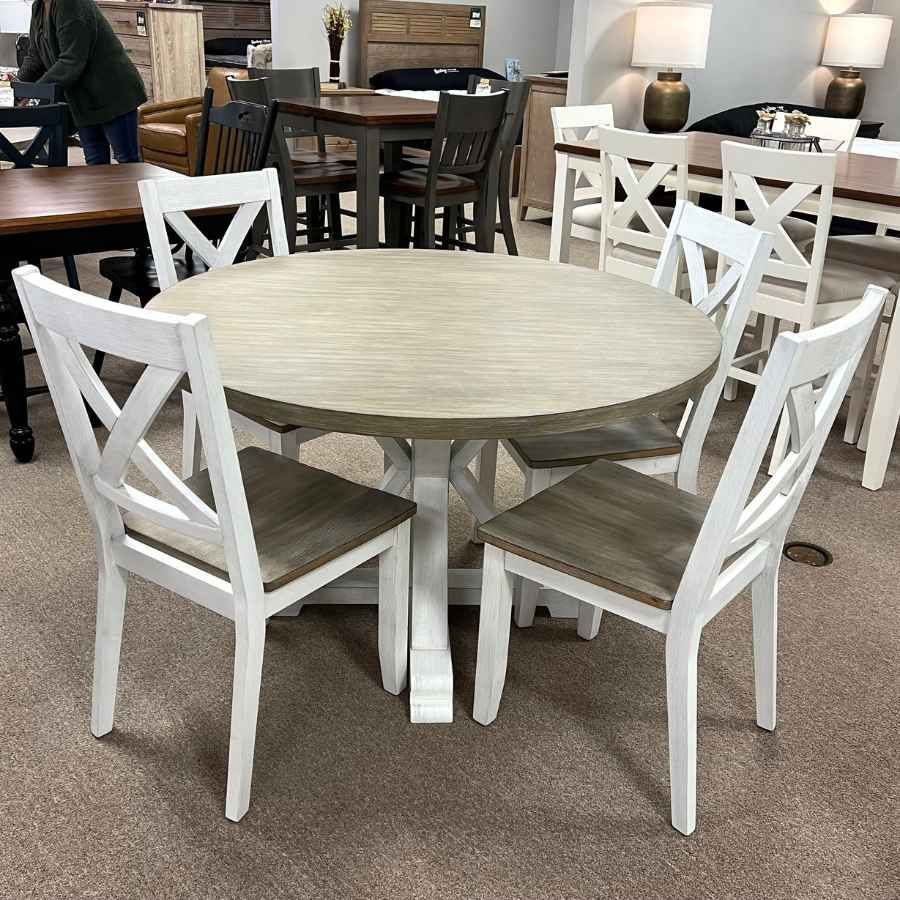 Round beige dining table with four white chairs in a furniture showroom