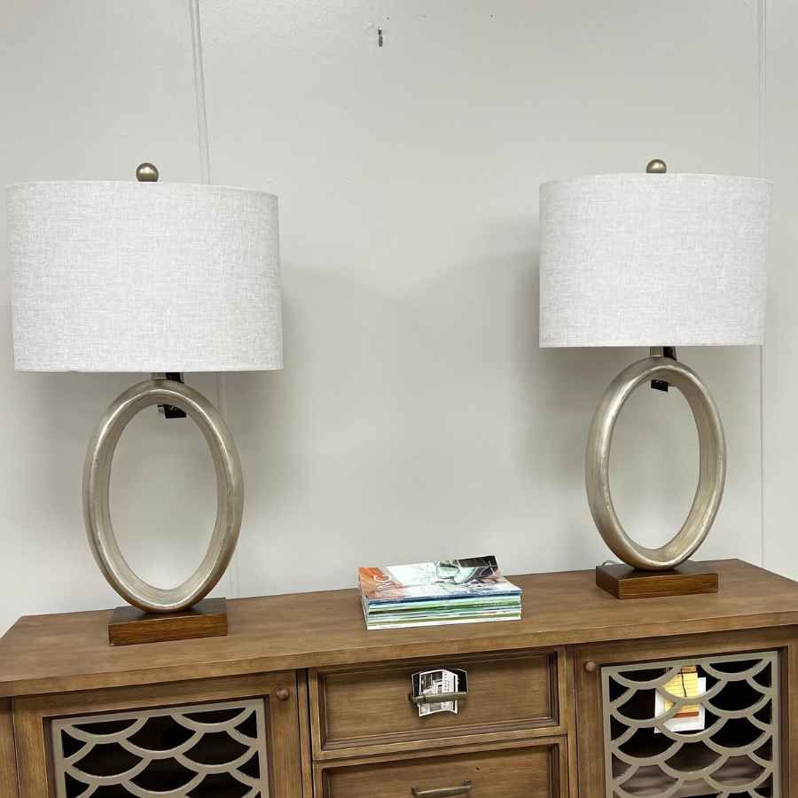Two matching white table lamps on a wooden console table with a small stack of books