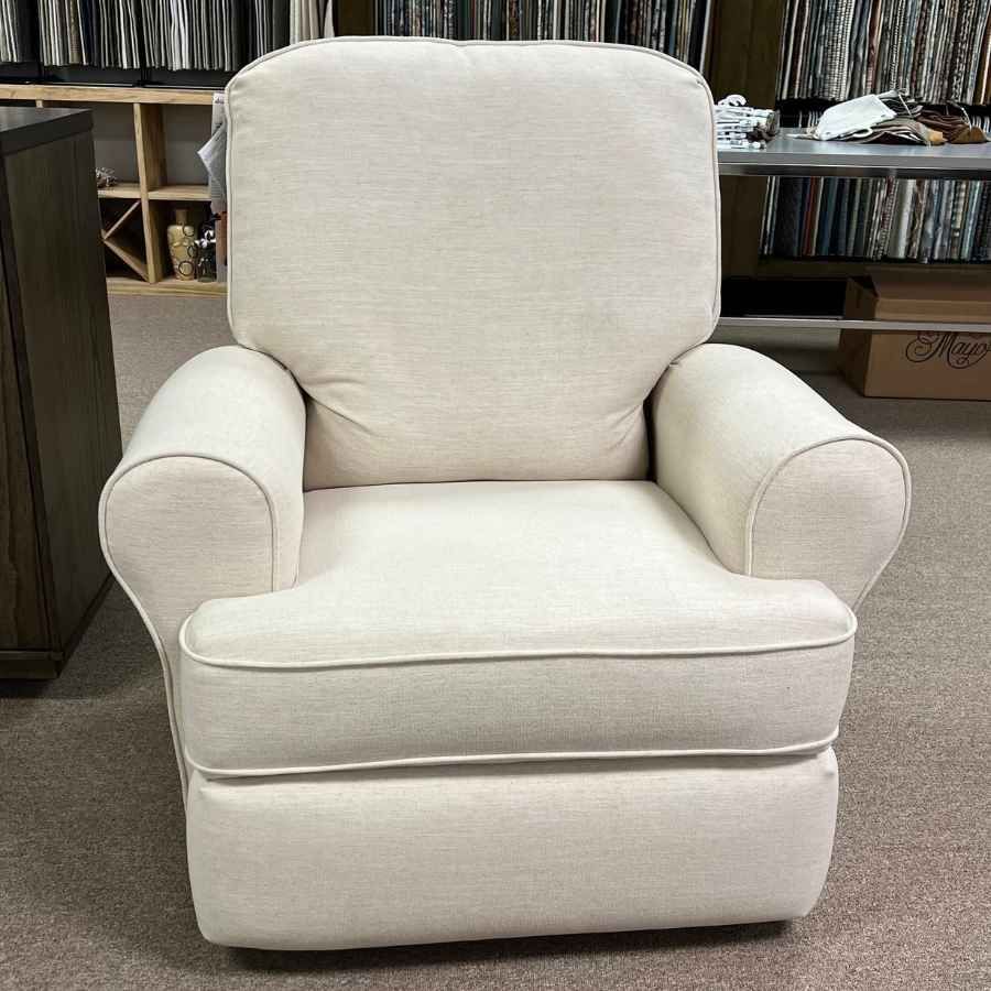 Cream upholstered armchair with rounded arms and cushioned base in a showroom or warehouse setting