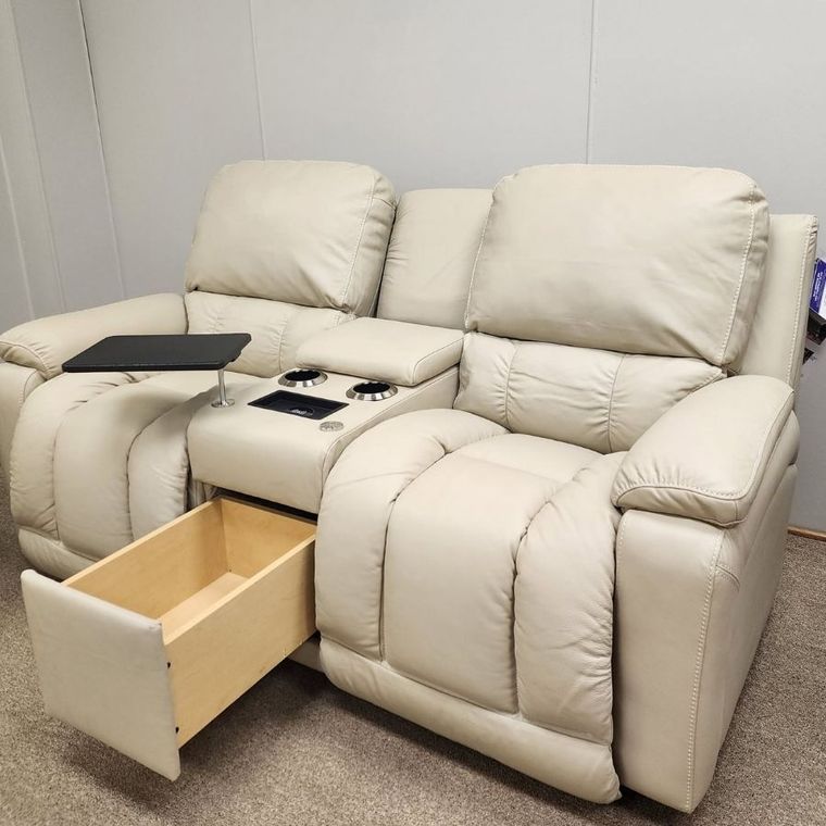 Beige recliner sofa with center console and cupholders, one drawer open, in a plain room