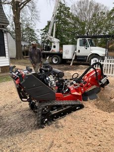 Red tracked snow plow attachment on the ground, with a worker and utility truck behind it.